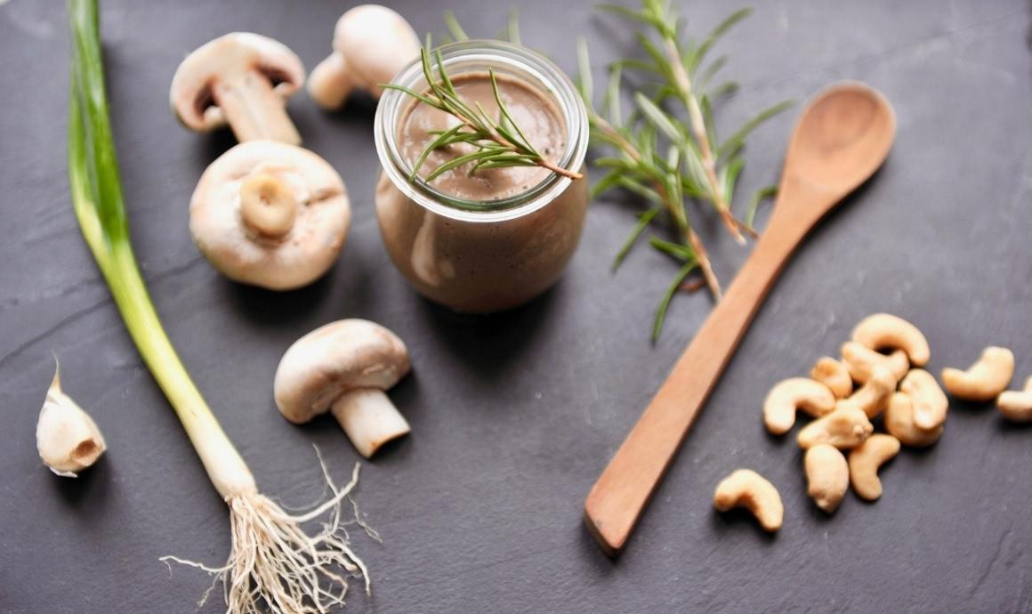 Cream of mushroom soup in glass on dark slate with ingredients.